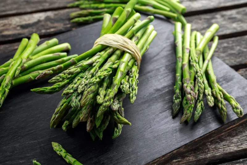 fresh raw green asparagus on wooden chopping board