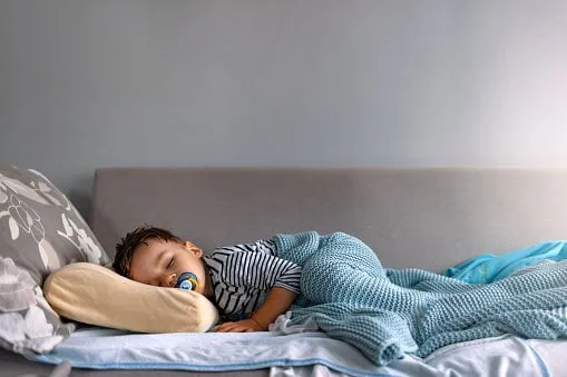 adorable little child boy sleeping in the bed facing the camera