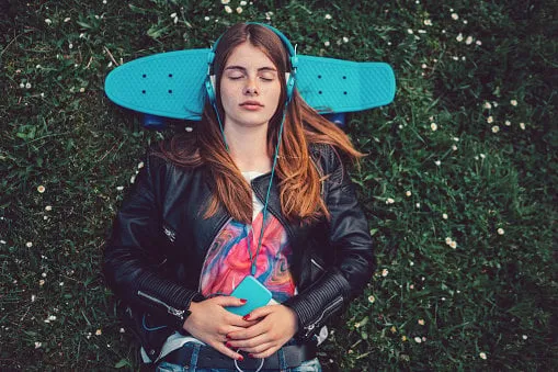 young woman lying down in the grass with skateboard behind head