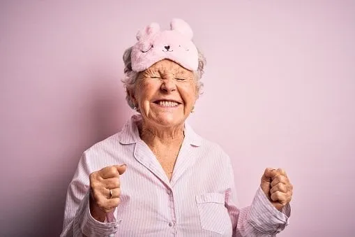 senior beautiful woman wearing sleep mask and pajama over isolated pink background excited for success with arms raised and eyes closed celebrating victory smiling winner concept