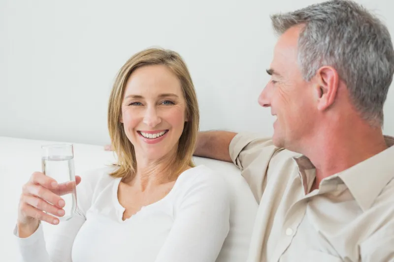 relaxed couple with a glass of water in living room at home