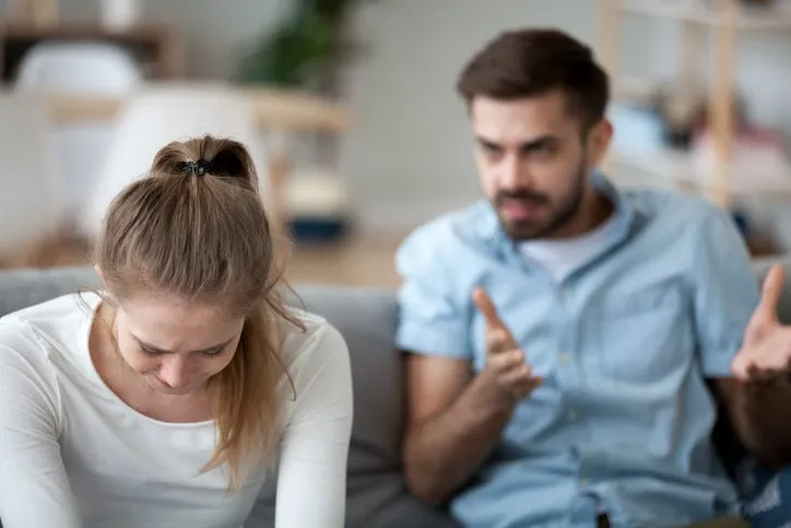 upset wife sit on couch crying listening to furious husband yelling, unhappy couple have fight or disagreement at home, sad woman feel desperate and down with mad spouse scolding and lecturing