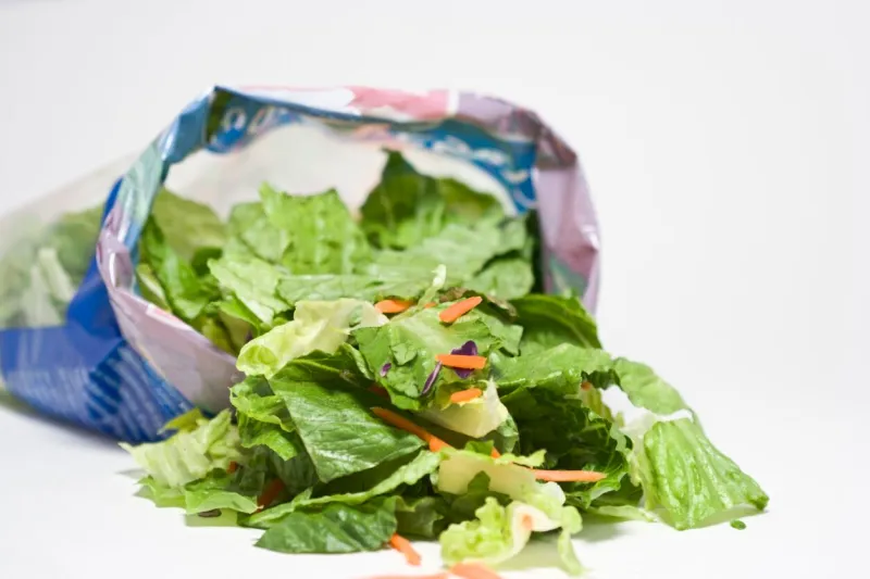 open bag of salad lettuce and carrots white background horizontal