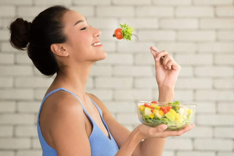 asian woman in joyful postures with hand holding salad bowl