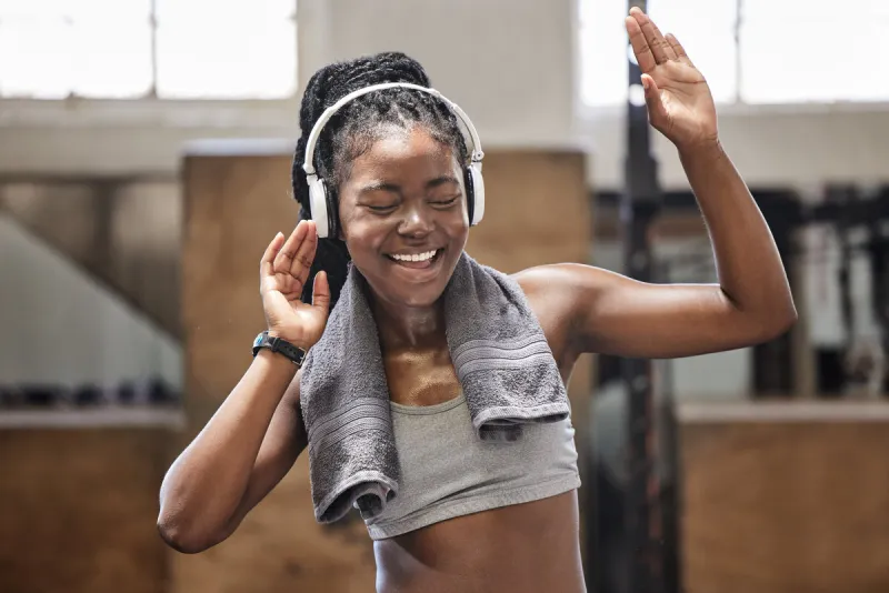 happy athlete singing and dance with headphone in a gym after fitness, exercise and training cheerful woman sweating having fun with music after health and wellness cardio workout in a sports club