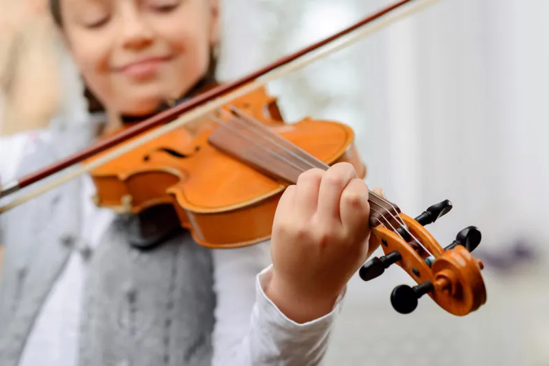 a way to success close up of pleasant vivacious pretty girl holding fiddle bow and learning to play the violin