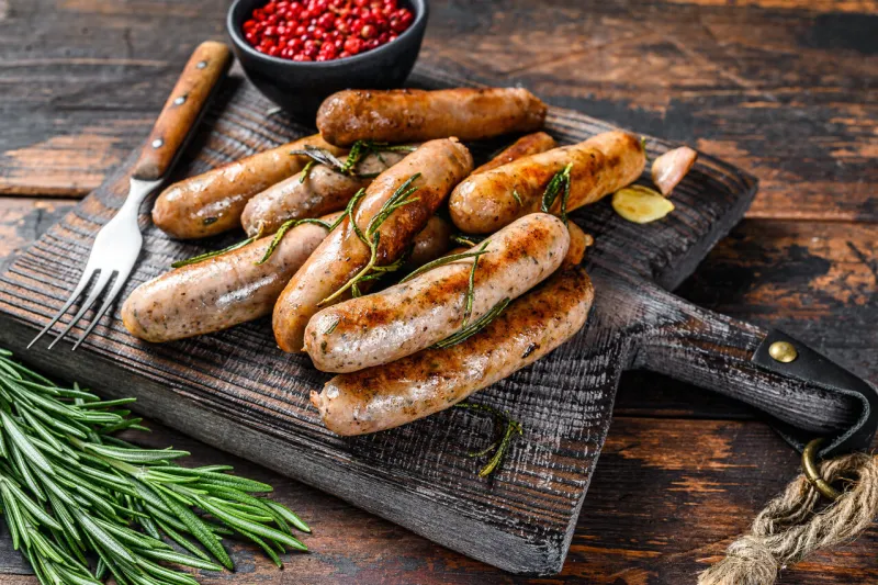 grilling bavarian sausages on a cutting board dark wooden background top view