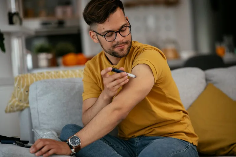 young man giving himself an insulin shot at home