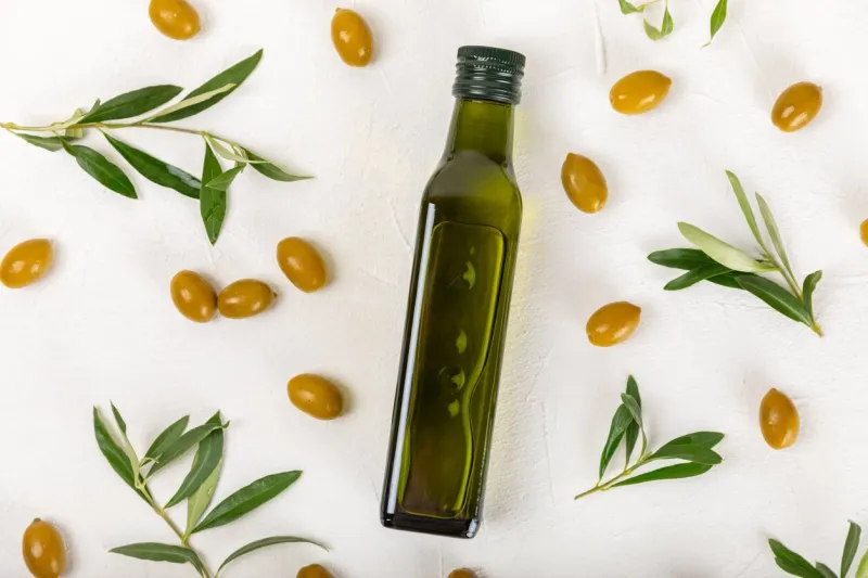 olive oil in a bottle on a white texture background oil bottle with branches and fruits of olives place for text copy space cooking oil and salad dressing
