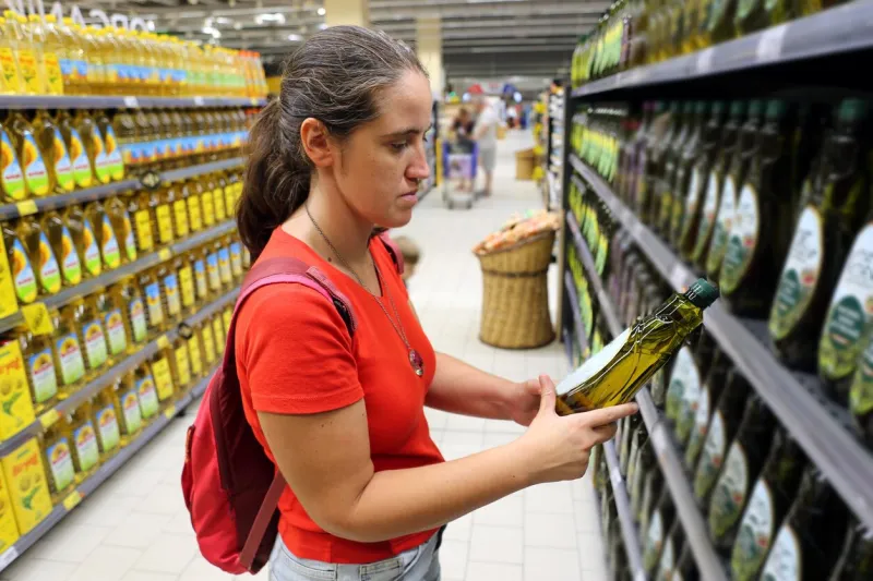 a female customer is interested in the content of olive oil grocery in store, supermarket