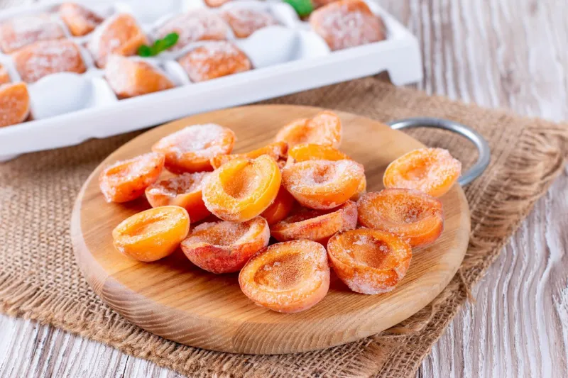 frozen apricots on a wooden board (slices, puree)