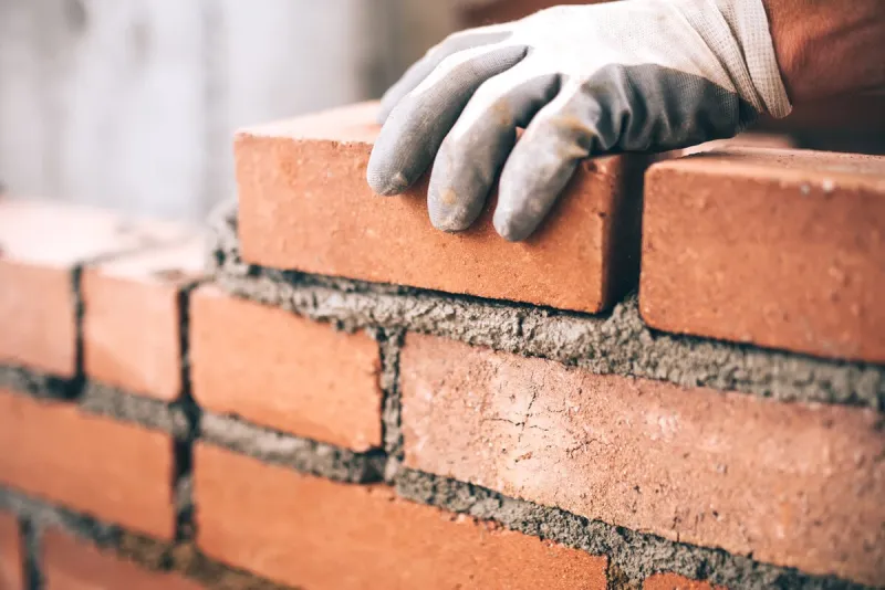 close up of industrial bricklayer installing bricks on construction site