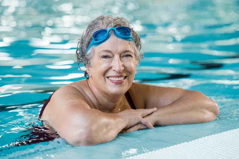 mature woman wearing swim goggles at swimming pool fit active senior woman enjoying retirement standing in swimming pool and looking at camera happy senior healthy old woman enjoying active lifestyle