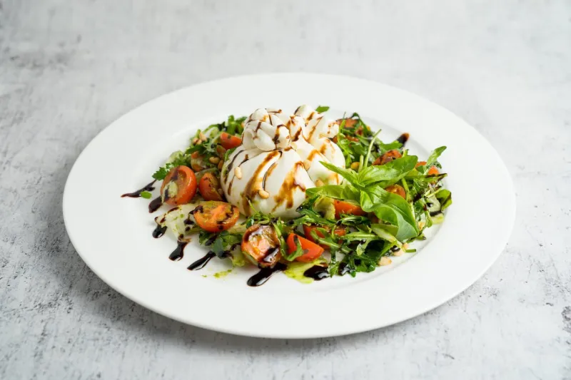 buffalo burrata cheese with vegetables and herbs on a plate, burrata cheese salad
