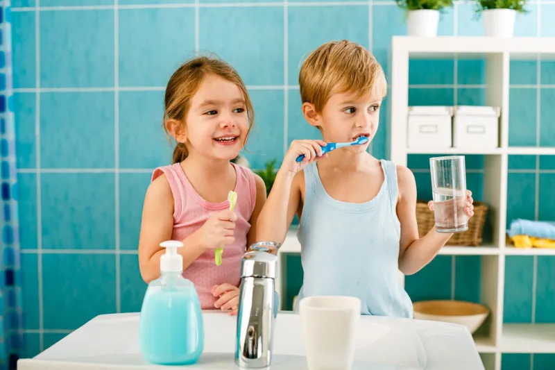 sibling brushing their teeth in the bathroom together