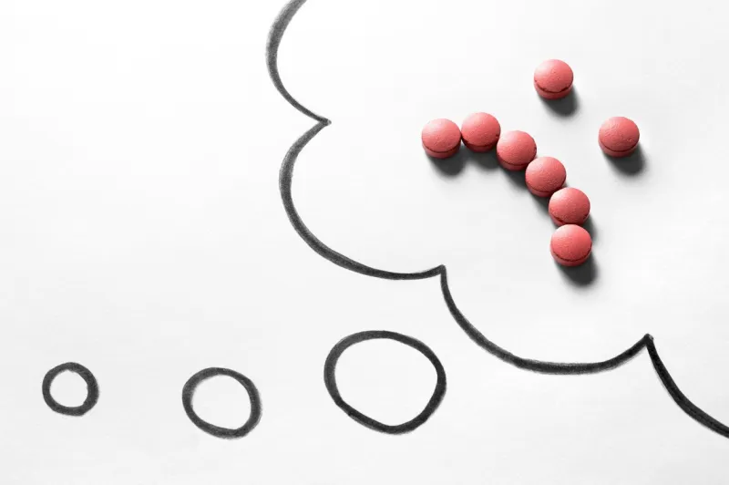 sad smiley face made from pills on hand drawn thinking speech bubble and thought cloud clinical depression, mental illness and disorder or bad health services concept