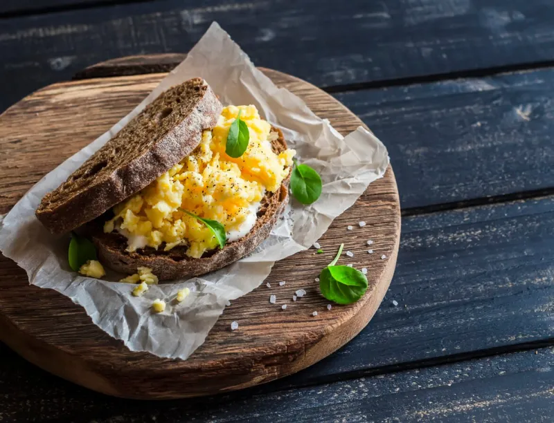 scramble egg sandwich on rustic wooden background healthy breakfast or snack