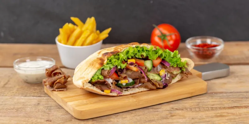 döner kebab doner kebap slice fast food in flatbread with french fries on a wooden board panorama sliced
