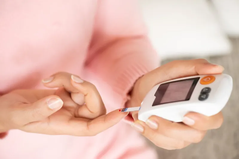 close up of woman hands checking blood sugar level by glucose meter for diabetes tester using as medicine, glycemia, healthcare and medical concept
