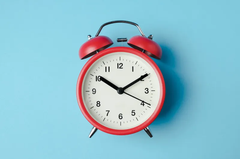 red vintage alarm clock on light blue color background