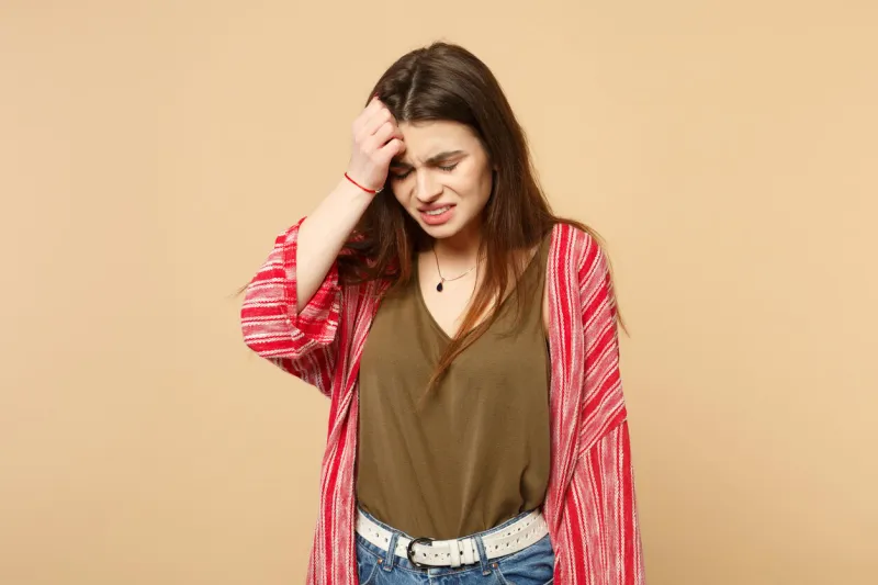 portrait of crying displeased young woman in casual clothes putting hand on head isolated on pastel beige wall background in studio people sincere emotions, lifestyle concept mock up copy space
