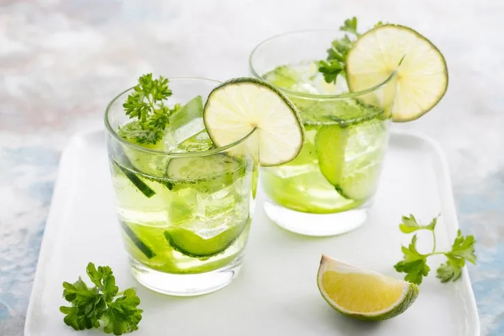 lime, cucumber, parsley cocktail, lemonade, detox water with ice cubes in a glasses on a white plate