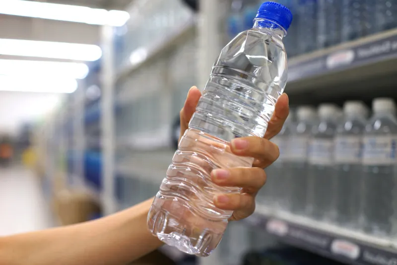 cropped hand buying water bottle in supermarket