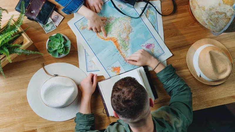 top view of unrecognizable young couple with maps planning vacation trip holiday, desktop travel concept
