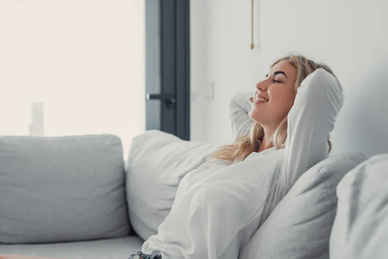 young calm woman chilling relaxing leaning on comfortable sofa napping on couch in living room resting having healthy quiet nap, breathing fresh air, no stress free weekend at home, peace of mind