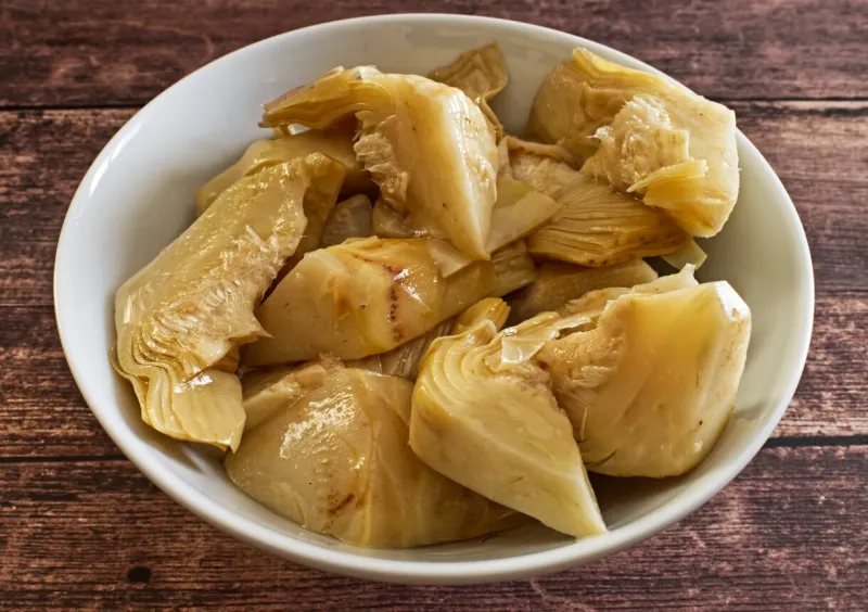 pickled artichokes in white bowl on wooden table