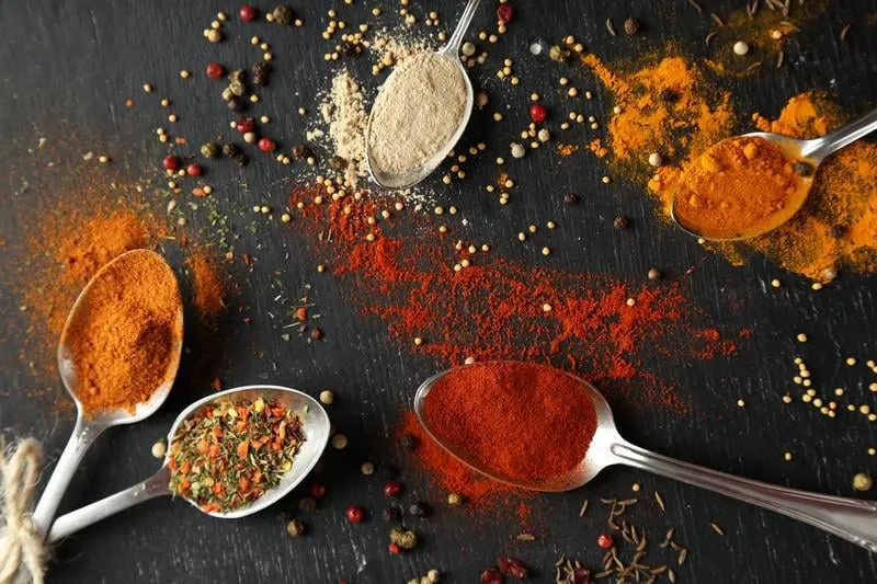 cuillères avec des épices sur une table en bois noire