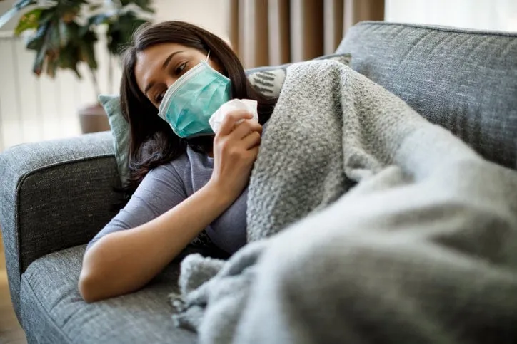 sick woman with face protective mask lying in bed