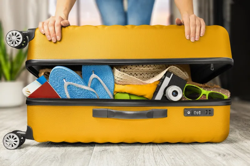 woman closes a full suitcase with things with both hands
