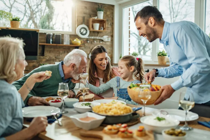 happy multi-generation family gathering around dining table and having fun during a lunch