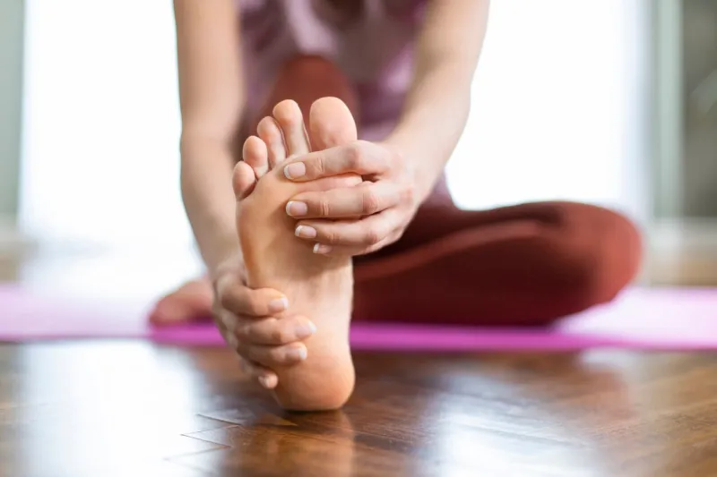 young woman feeling pain in her foot while exercise at home