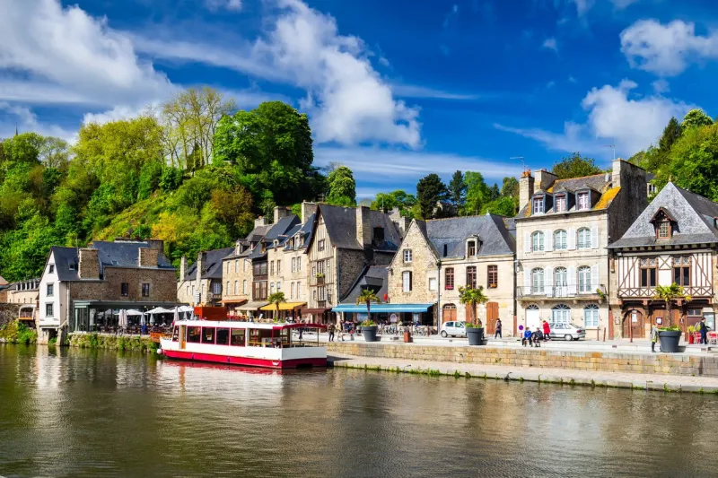 beautiful view of scenic narrow alley with historic traditional houses and cobbled street in an old town of dinan with blue sky and clouds brittany (bretagne), france