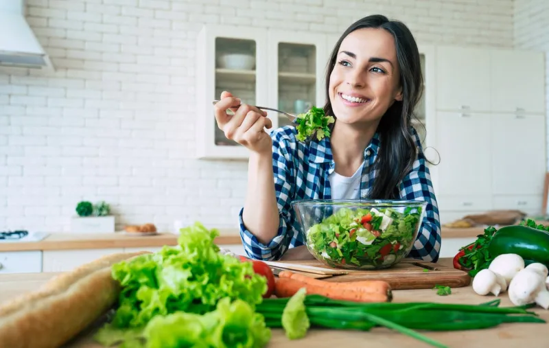 healthy lifestyle good life organic food vegetables close up portrait of happy cute beautiful young woman while she try tasty vegan salad in the kitchen at home