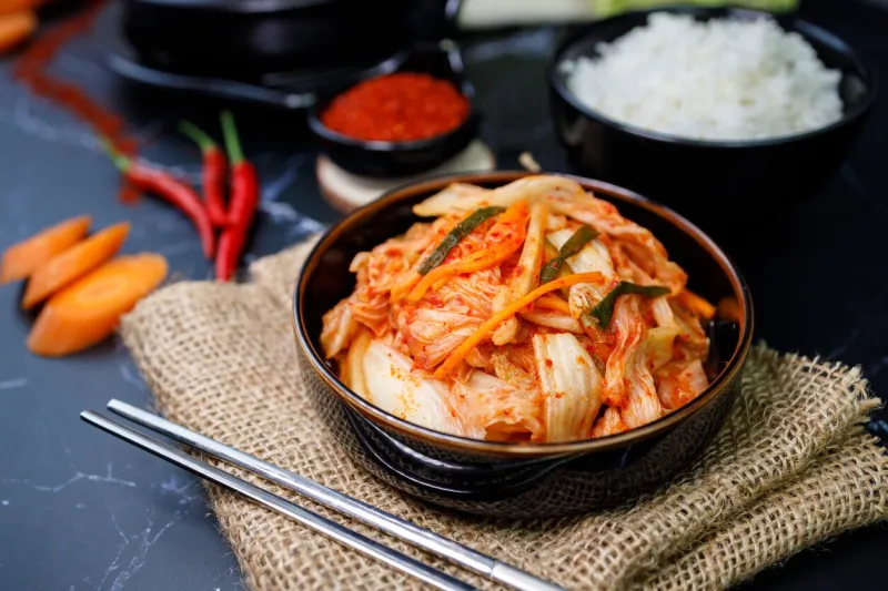 eating kimchi cabbage and rice in a black bowl with chopsticks, korean food