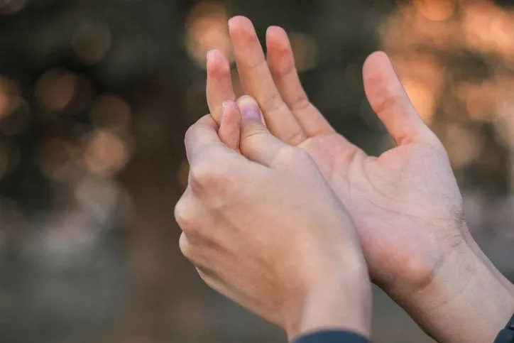 young woman with pain on finger, bokeh background