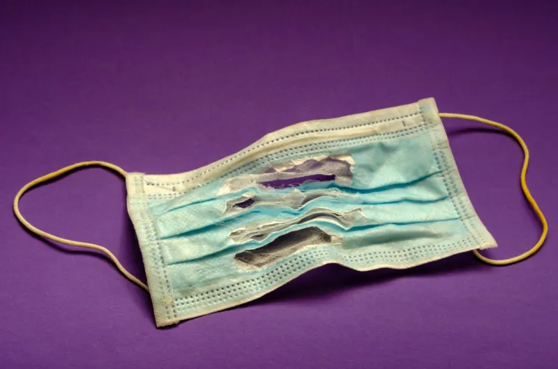 torn medical mask a single used mask on the table old mask on a lilac background selective focus close-up