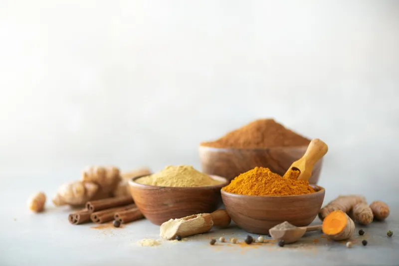 ingredients for turmeric latte ground turmeric, curcuma root, cinnamon, ginger, black pepper on grey background spices for ayurvedic treatment alternative medicine concept