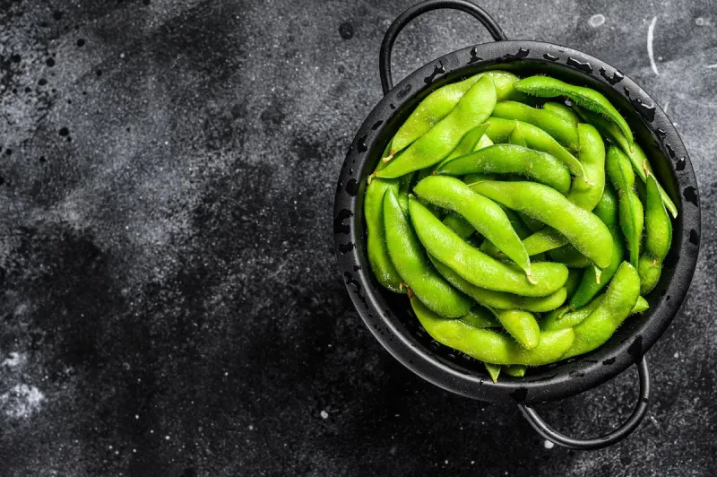 raw beans edamame in the colander black background top view copy space