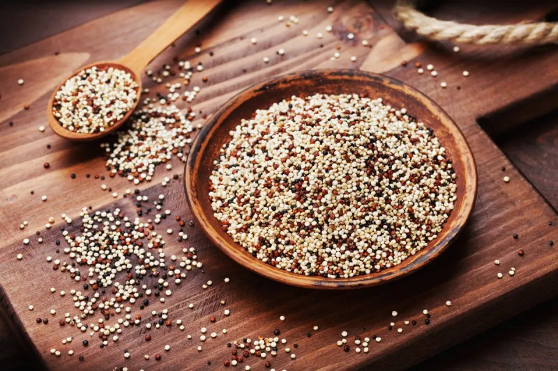 mixed quinoa in bowl on wooden kitchen board