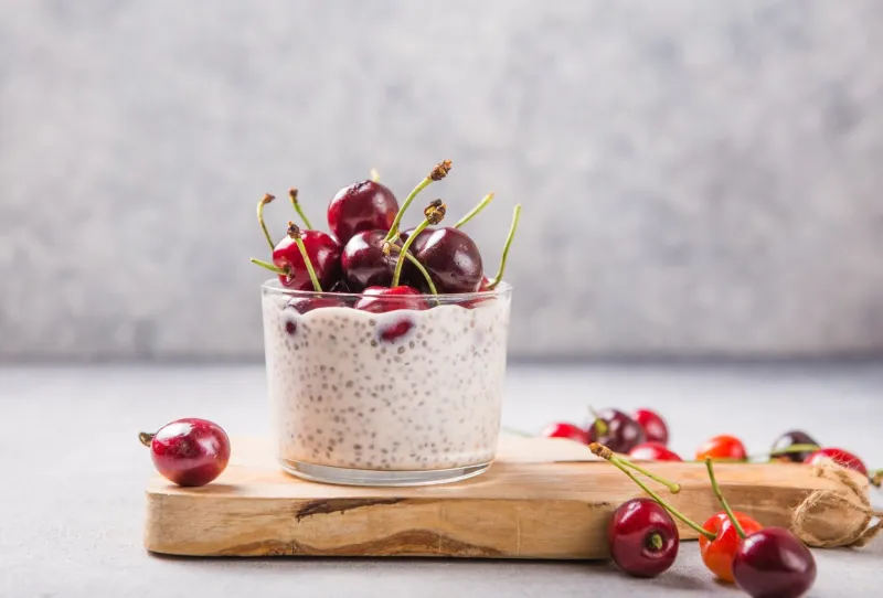 chia pudding with cherry berries, natural yogurt, in a glass on a grey surface selective focus healthy dessert, proper nutrition, super food