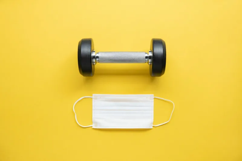 gym background with fitness equipment dumbbell and n95 mask concepts stay safe workout at home