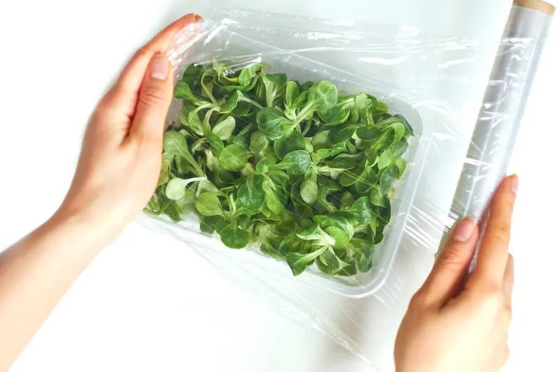 woman using food film for food storage on a white table roll of transparent polyethylene food film for packing products