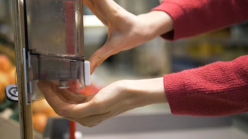 woman's hands close-up disinfects her hands with a sanitizer in a grocery supermarket protection from the coronavirus pandemic rules of personal hygiene against covid-19