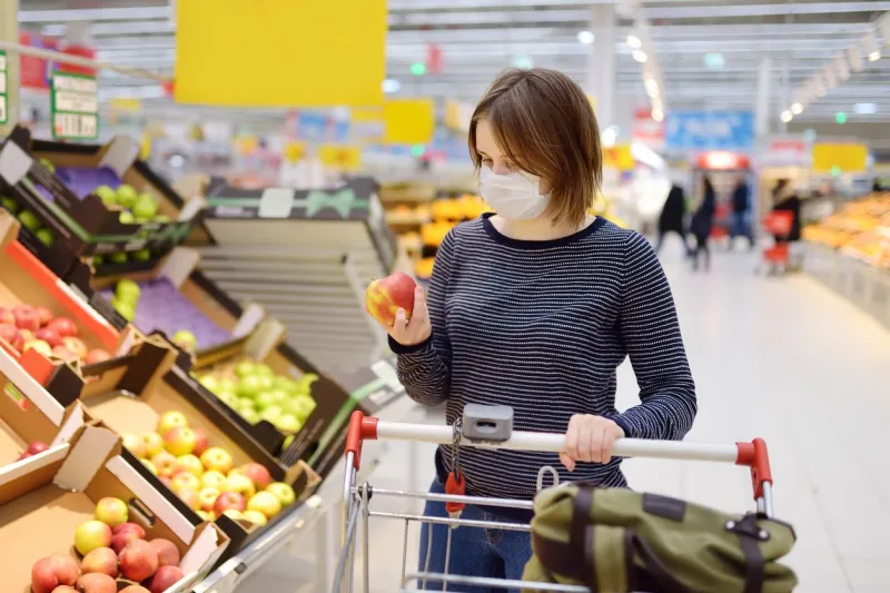 young woman wearing disposable medical mask shopping in supermarket during coronavirus pneumonia outbreak protection and prevent measures while epidemic time
