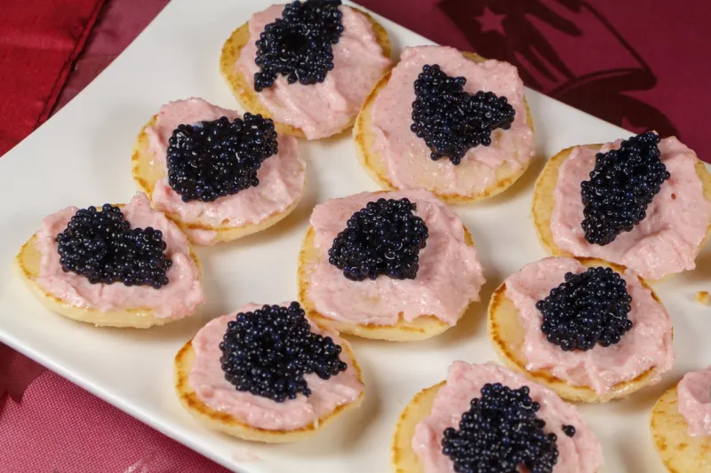 blinis with taramasalata and lump-fish roe on a white dish