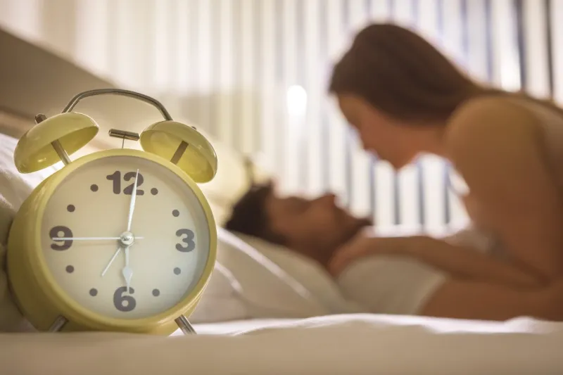 the clock on the background of the couple in the bed